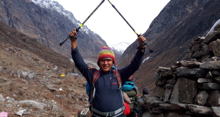 Man holding trekking poles on a mountainous trail.