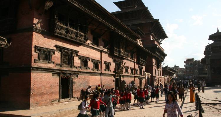 Historisch bakstenen paleis met fraai uitgesneden houten ramen aan een druk plein vol schoolkinderen