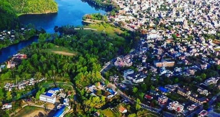 Vue aérienne d'une ville au bord d'un lac entourée de forêts.