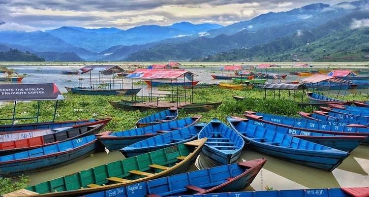 Bateaux colorés sur un lac avec des montagnes en arrière-plan.