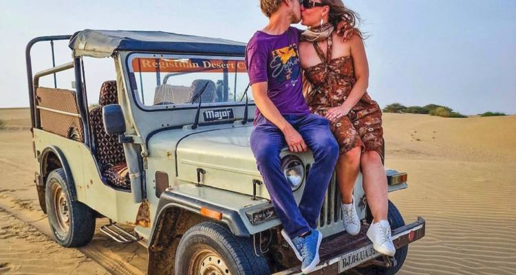Paar sitzt auf einem Jeep in einer Wüstenszene.