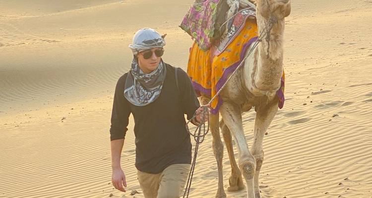 Person, die ein Kamel durch die Wüste führt.