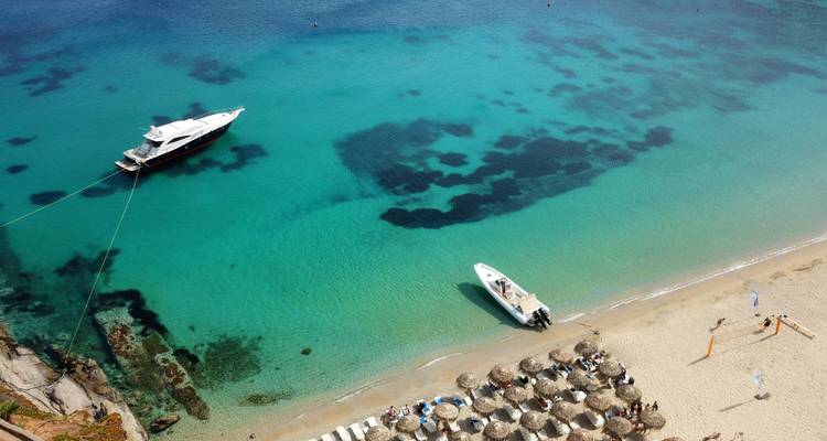 Vue aérienne de bateaux et d'une plage avec une eau turquoise cristalline.