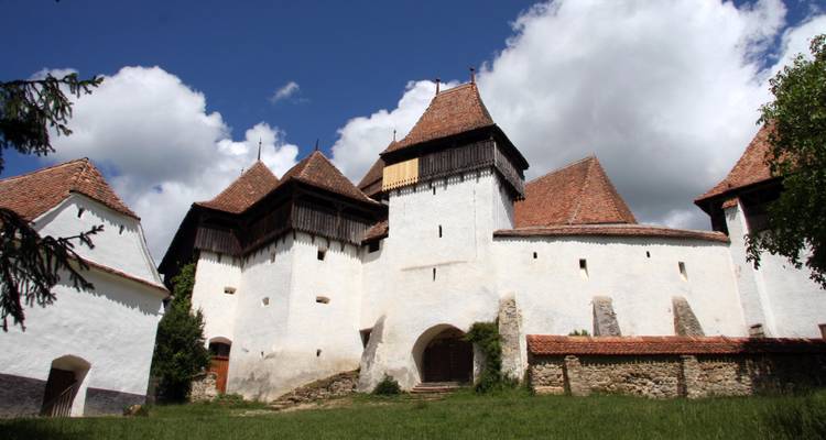 Medieval fortified church with white walls and towers.