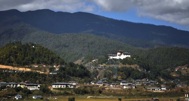 Vue panoramique d'une vallée bhoutanaise avec un monastère.
