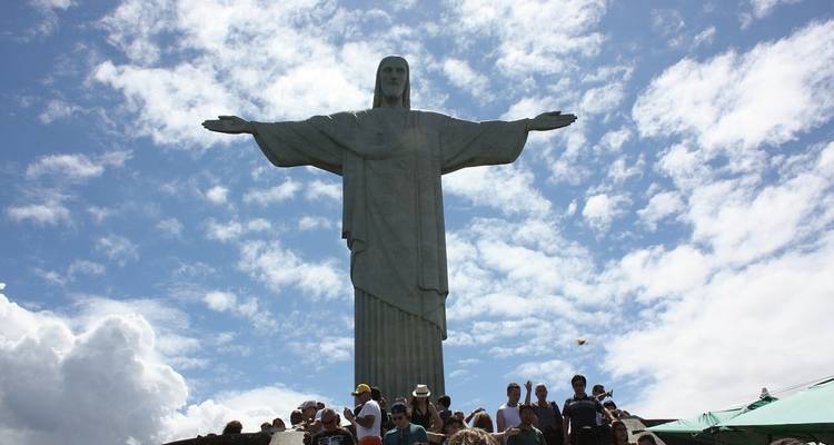 Estatua del Cristo Redentor con personas reunidas abajo.