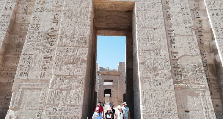 Des touristes qui se promènent dans un temple ancien avec des hiéroglyphes.