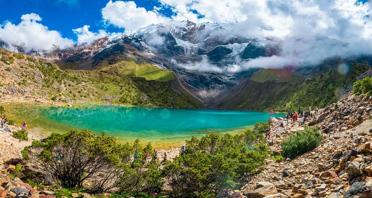 Turistas alrededor de un lago turquesa con montañas impresionantes.
