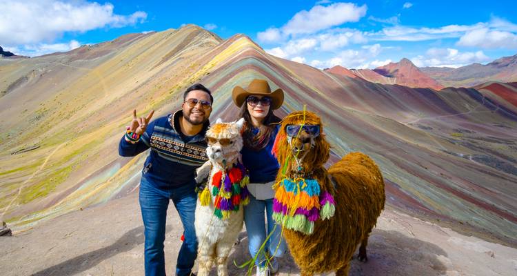 Pareja posando con llamas decoradas en la Montaña Arcoíris.