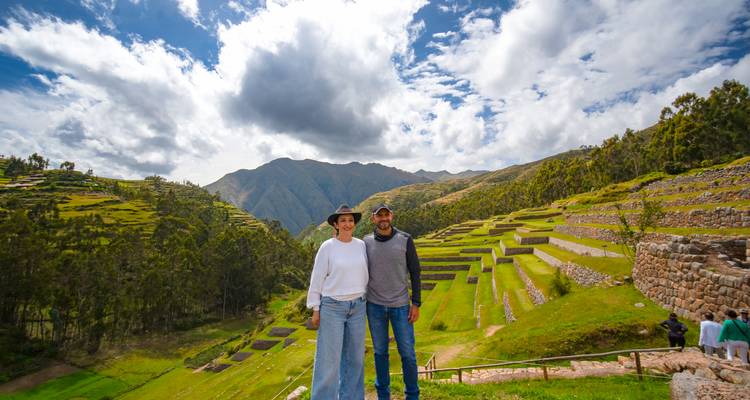 Pareja posando frente a campos de terrazas bajo un cielo parcialmente nublado.