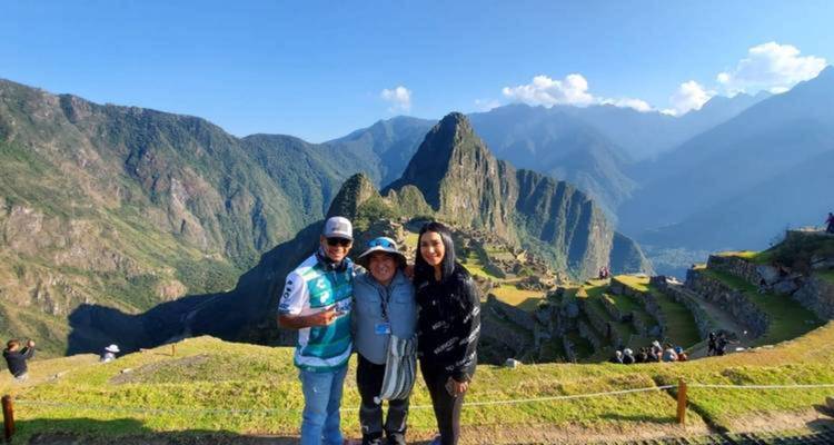 Los viajeros posan con las icónicas terrazas de Machu Picchu y el pico Huayna Picchu detrás de ellos.
