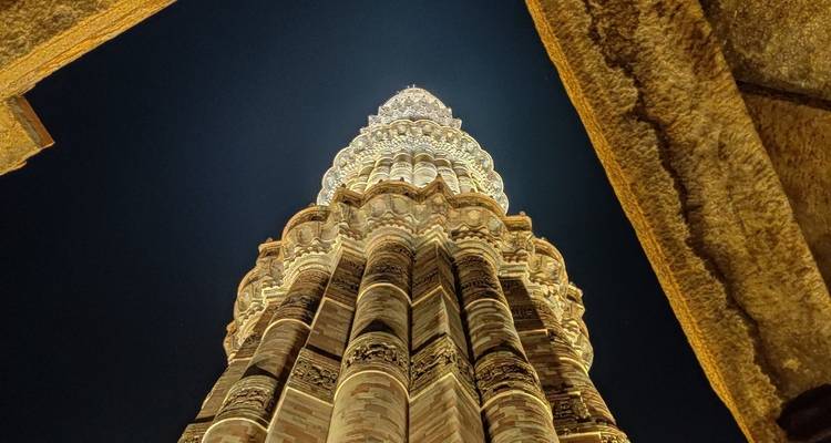 Haut minaret de pierre vu d'en bas la nuit, finement sculpté.