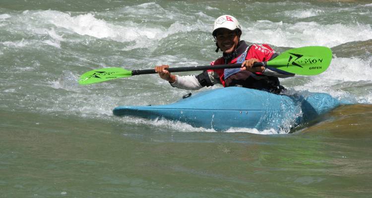 Homme souriant faisant du kayak dans une rivière.