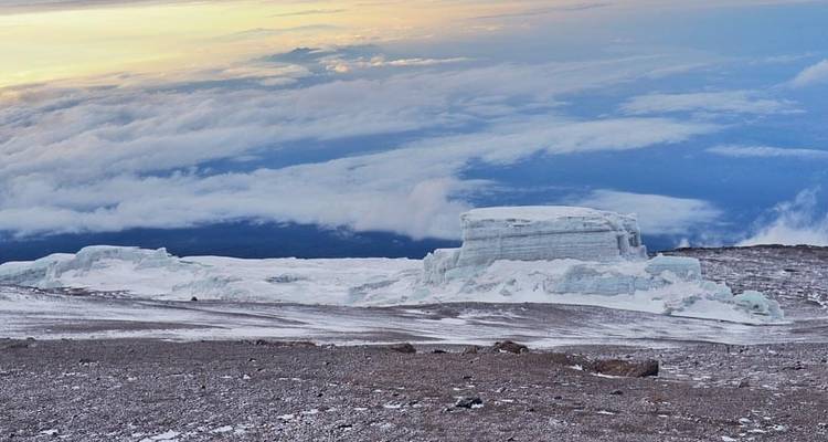Expansive glaciers with a sunset sky above clouds.