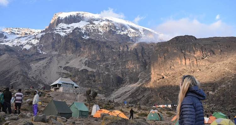 Camping tents set up at the base of a snowy mountain.