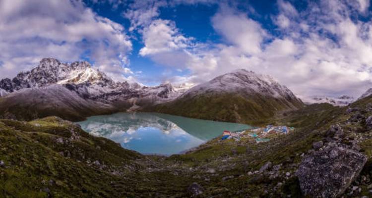 Montañas cubiertas de nieve y un lago glacial con un pequeño asentamiento.