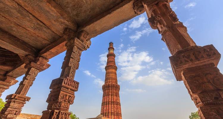 Historischer Qutub Minar, eingerahmt von Säulen.