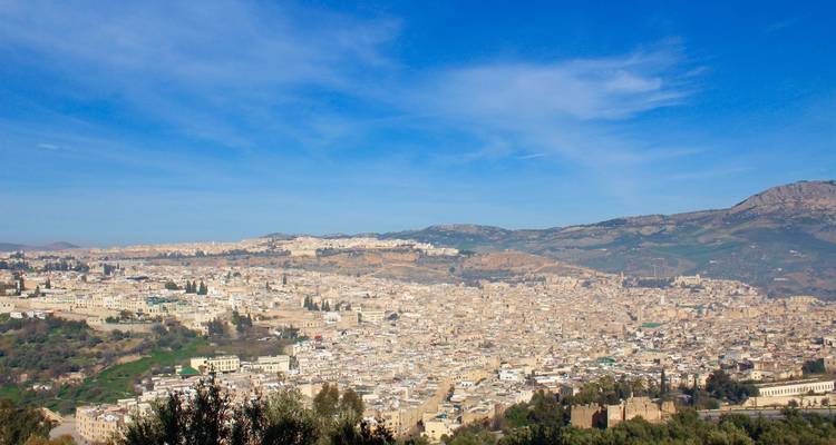 Panoramablick auf eine Stadt mit sanften Hügeln im Hintergrund.