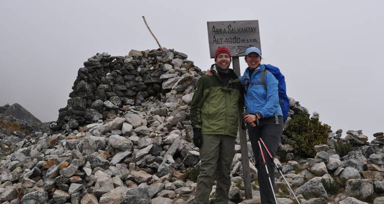 Two hikers standing by a rock pile with an altitude sign.