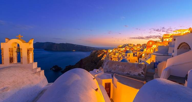 Santorini rooftops glowing during twilight over the Aegean Sea.
