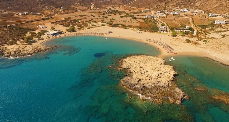 Luchtfoto van een strand met helder water en rotsachtige kaap.