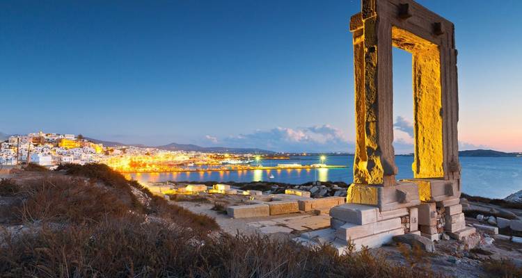 La Portara de Naxos au crépuscule, surplombant la mer et les lumières de la ville.
