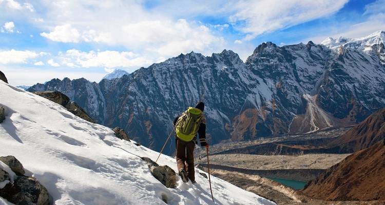 Hiker trekking through snowy mountains with scenic views.
