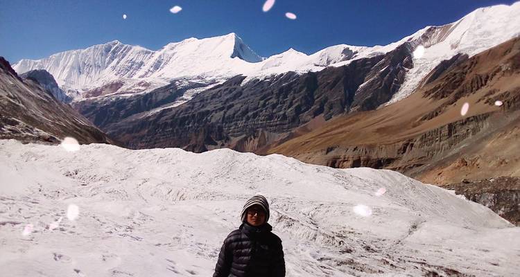 Person, die vor einer schneebedeckten Berglandschaft steht.