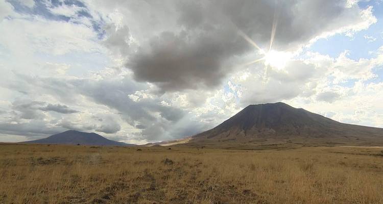 Landschapszicht met glooiende heuvels en een bergachtige achtergrond.