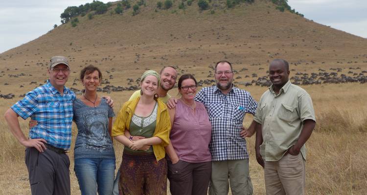 Group of people posing in front of a hill in the savannah.