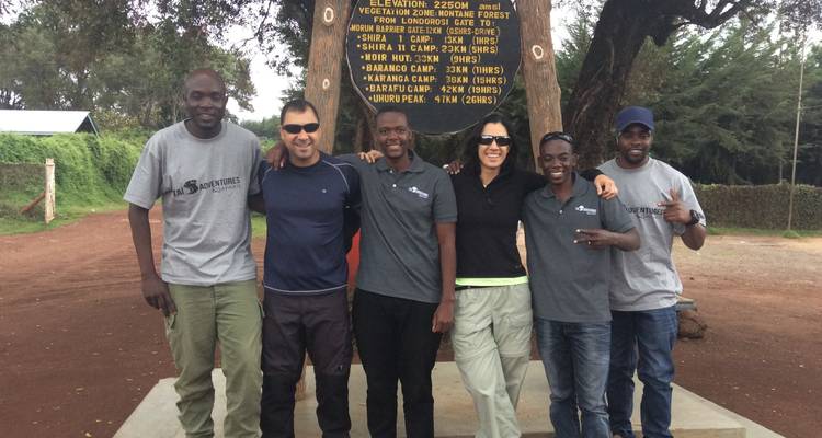 Group of people posing under a camp sign.