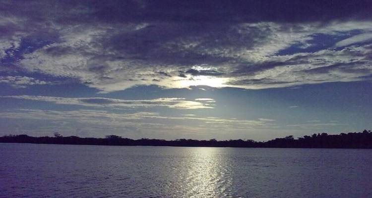 Malerische Aussicht auf einen See oder Fluss mit dramatischen Wolken und Sonnenlicht.