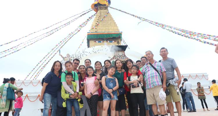 A group of people posing in front of a large stupa with prayer flags.