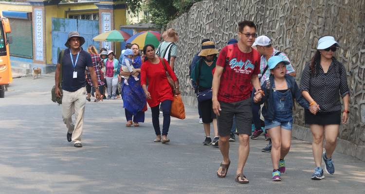 Several people walking along a street, some holding umbrellas.