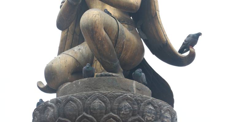 Statue of a deity with pigeons perched on it.