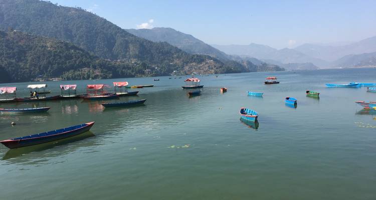 Boote, die auf einem ruhigen See treiben, mit Bergen in der Ferne.