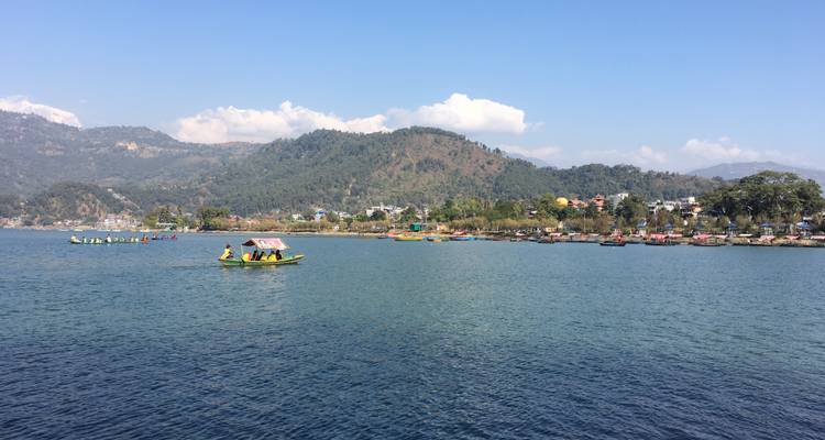 Malerische Aussicht auf einen See mit Booten und Hügeln im Hintergrund.