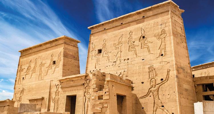 Ancient Egyptian temple with carved walls under a blue sky.