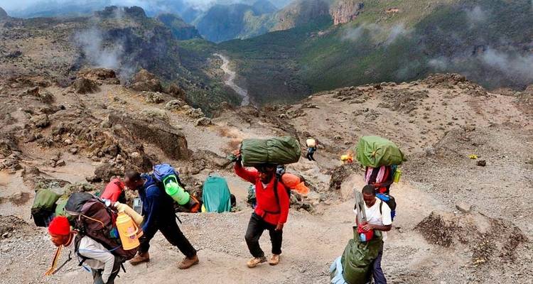 Un groupe de porteurs transportant des charges sur un sentier de montagne.