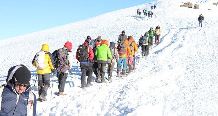 Un grupo de escaladores caminando a través de terreno cubierto de nieve.