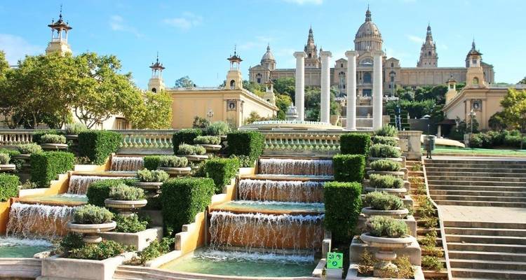 Fuentes ornamentadas con un edificio histórico al fondo.