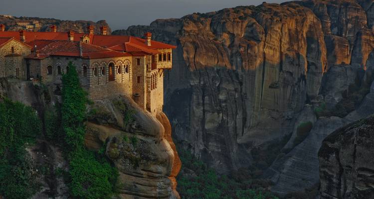 Monastère construit sur une formation rocheuse au coucher du soleil.
