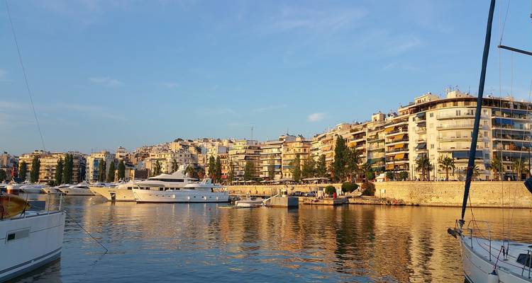 Vue d'un port de plaisance urbain avec des yachts and des bâtiments au coucher du soleil.