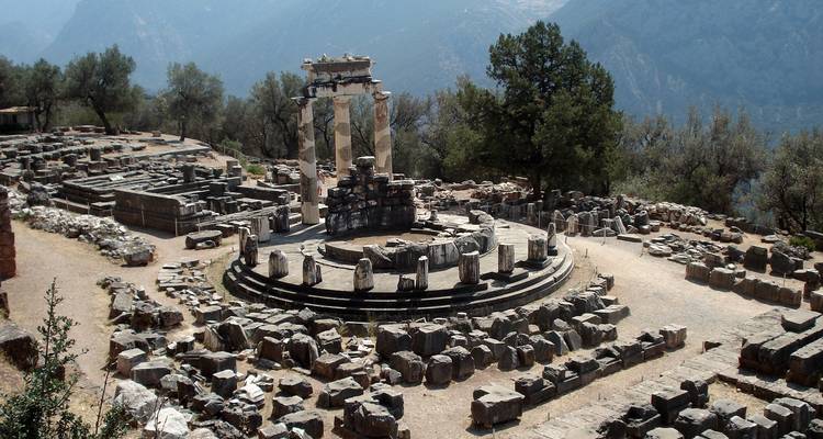 Ruines anciennes dans un cadre montagneux avec un temple circulaire.