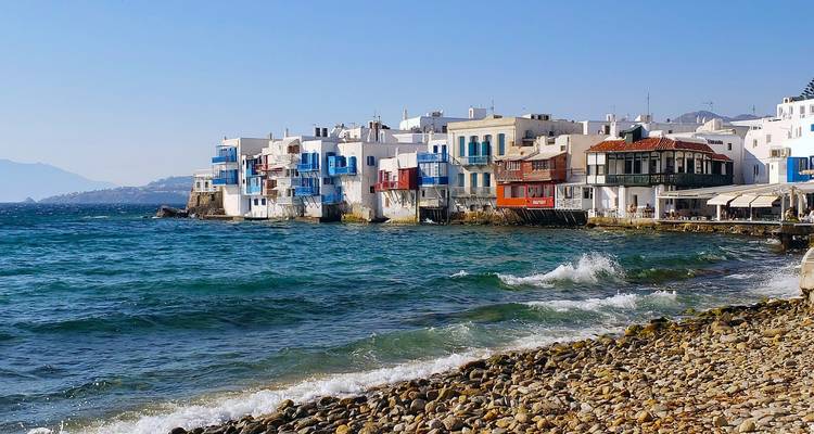 Casas coloridas a orillas del agua de la Pequeña Venecia en Mykonos junto a las brillantes olas azules del Egeo.