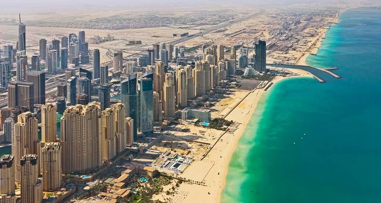 Aerial view of a city with modern skyscrapers and a coastline.