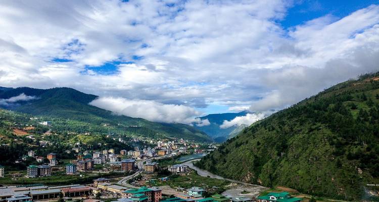 Un valle con un río, rodeado de montañas y nubes.