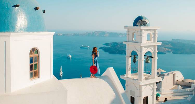 Mujer en una azotea blanca con vista al mar y los edificios.