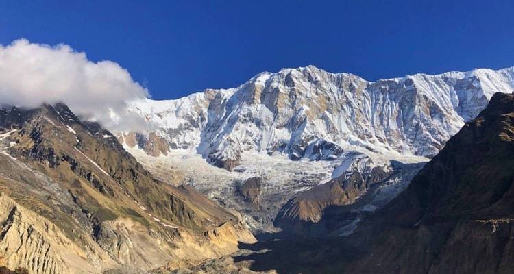 Panoramisch uitzicht op het Annapurna-gebergte bedekt met sneeuw onder een heldere blauwe hemel.