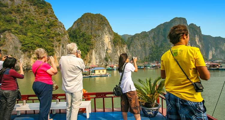 Toeristen die schilderachtige kalksteenformaties fotograferen vanaf een boot.